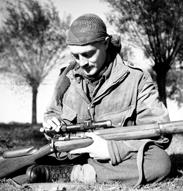 Sergeant H.A. Marshall of The Calgary Highlanders cleans the telescopic sight of his No.4, MkI(T) rifle during a scouting, stalking and sniping course, Kapellen, Belgium, 6 October 1944.