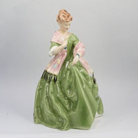 China figurine of lady in wide green dress with pink shawl trimmed in black